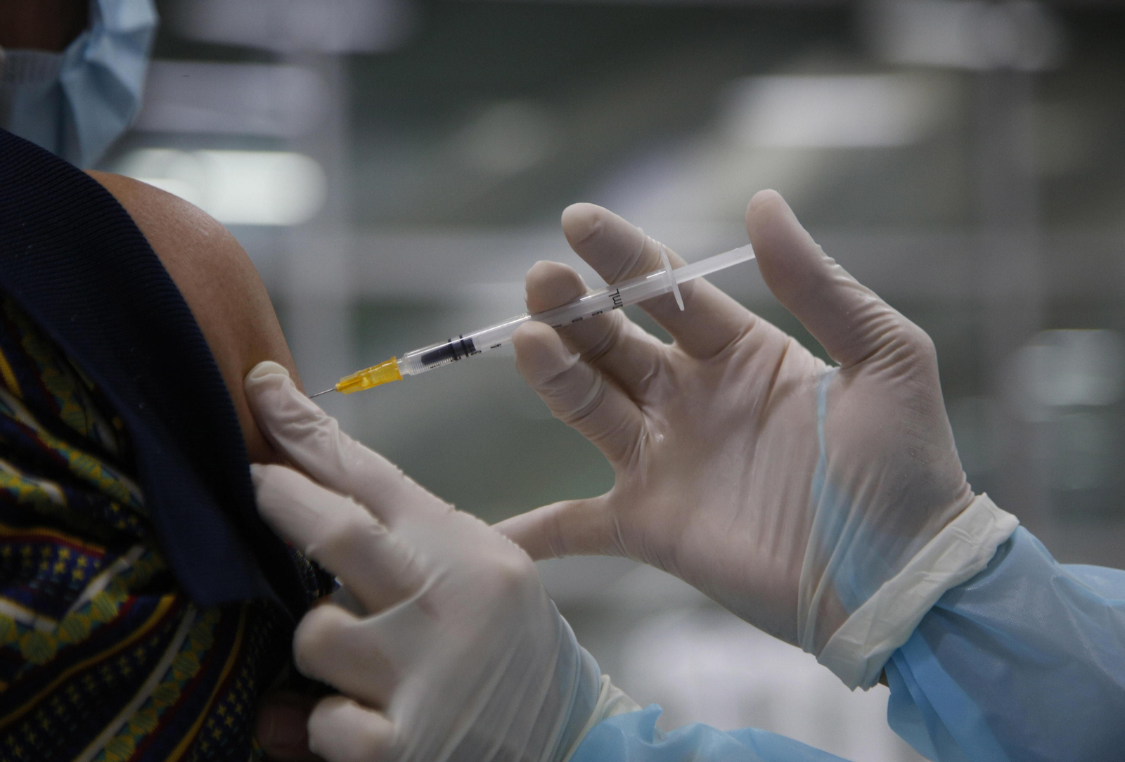 Un sanitario inocula una vacuna a un paciente