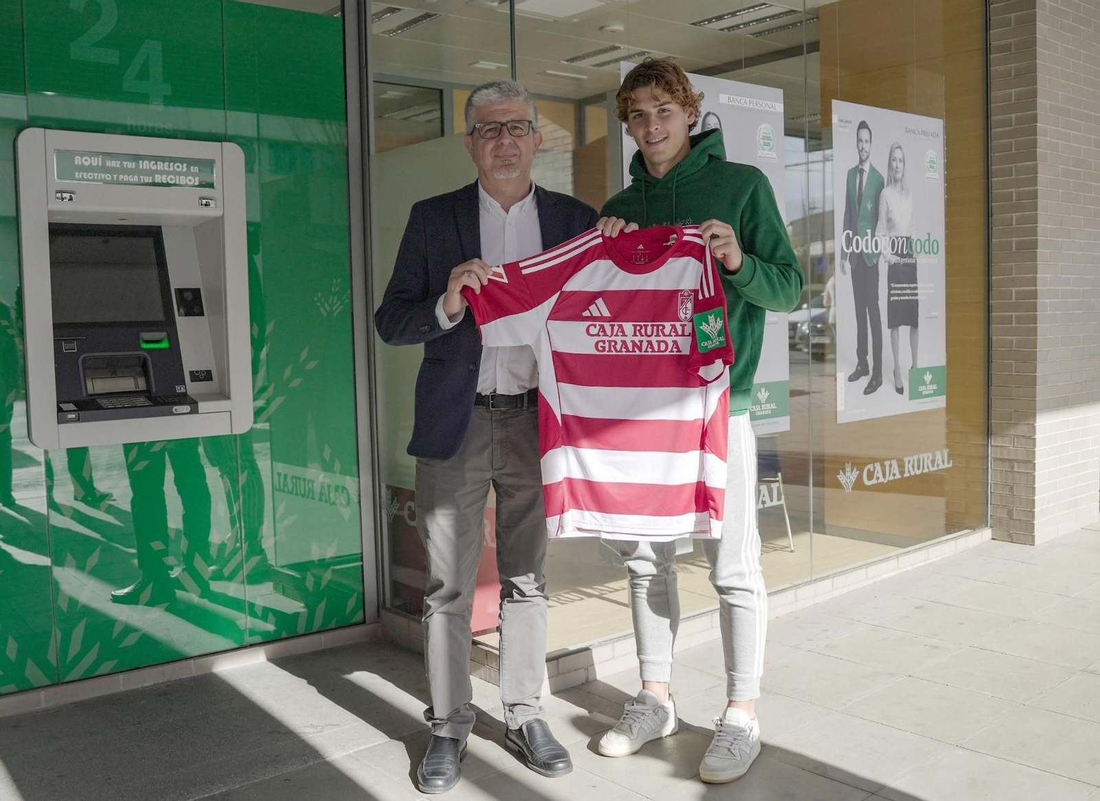 El director de Negocio José Aurelio Hernández junto al delantero Jorge Pascual con la nueva camiseta del Granada CF.