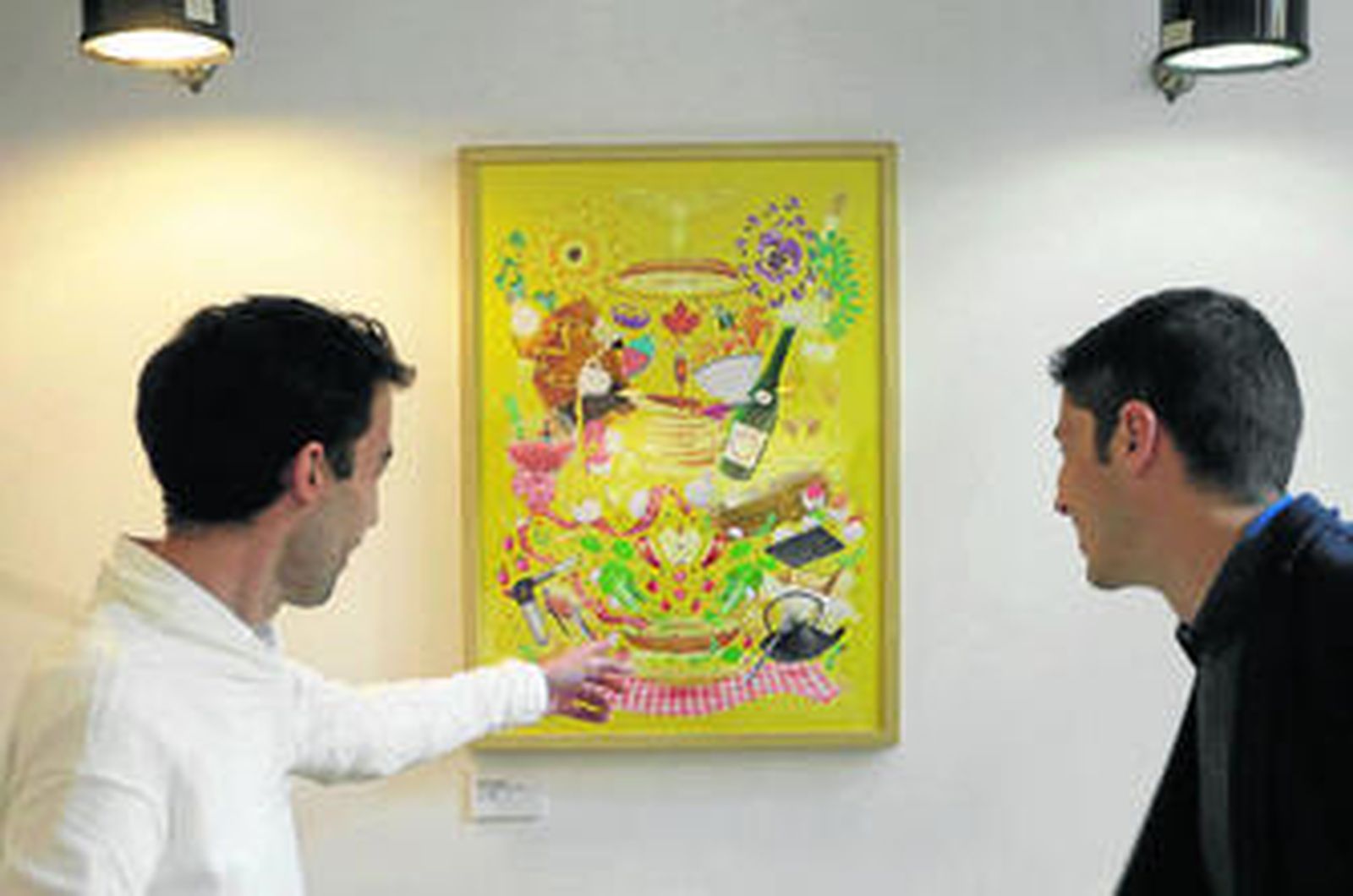 Miguel Parra, uno de los propietarios de Kök Tu cocina, muestra a uno de los visitantes un pieza de la muestra.