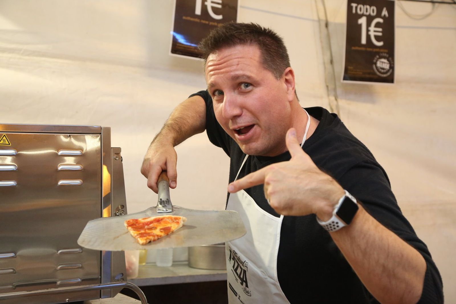 Un cocinero de uno de los once establecimientos que participan en el evento, mostrando una porción de pizza.
