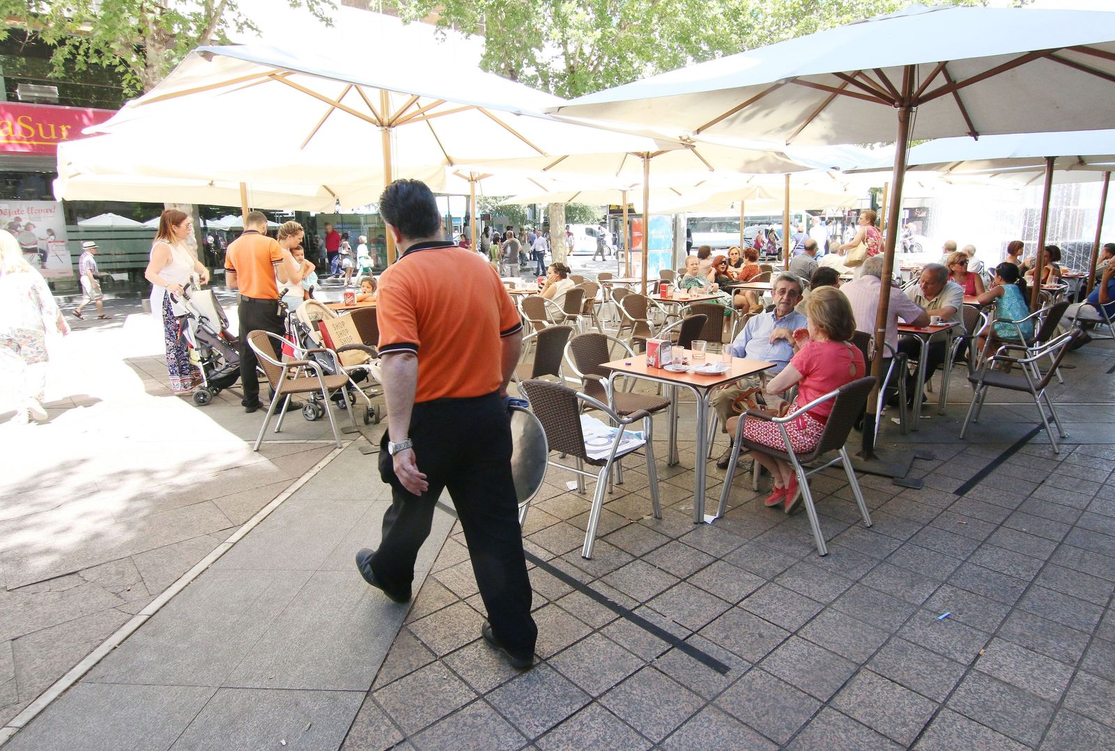 Varios camareros trabajan en la terraza de un bar.
