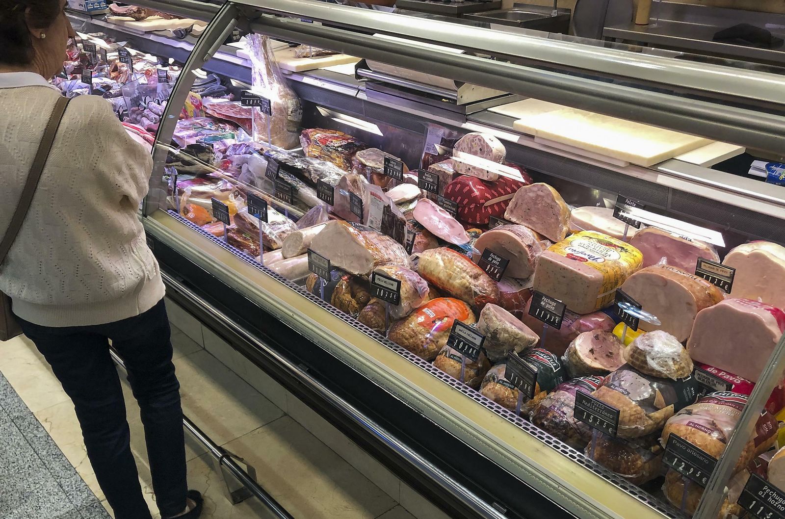 Una mujer mira un expositor de embutidos en un establecimiento de Sevilla.