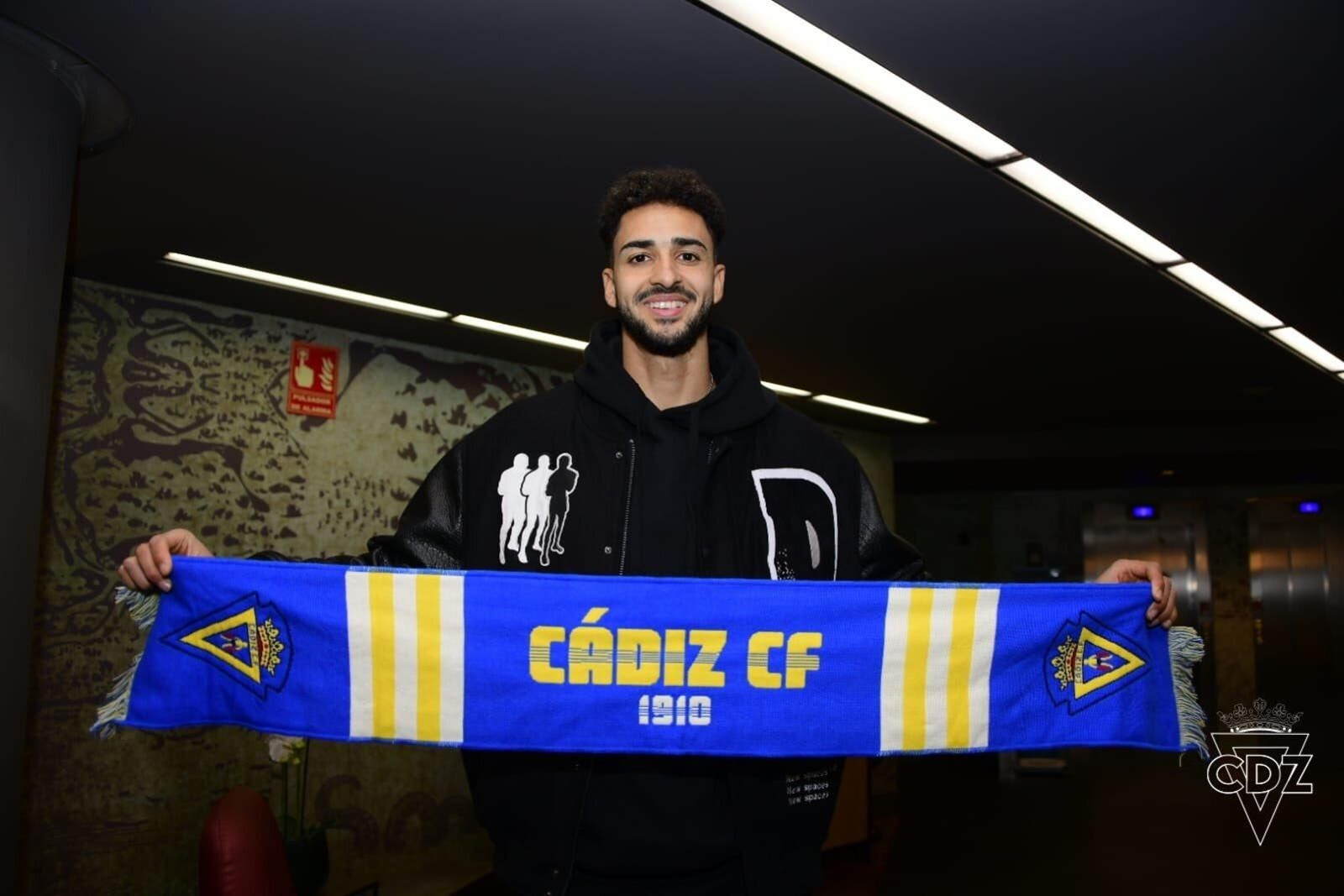 Chris Ramos posa con la bufanda del equipo de sus amores a la llegada a la ciudad en la noche de este miércoles.