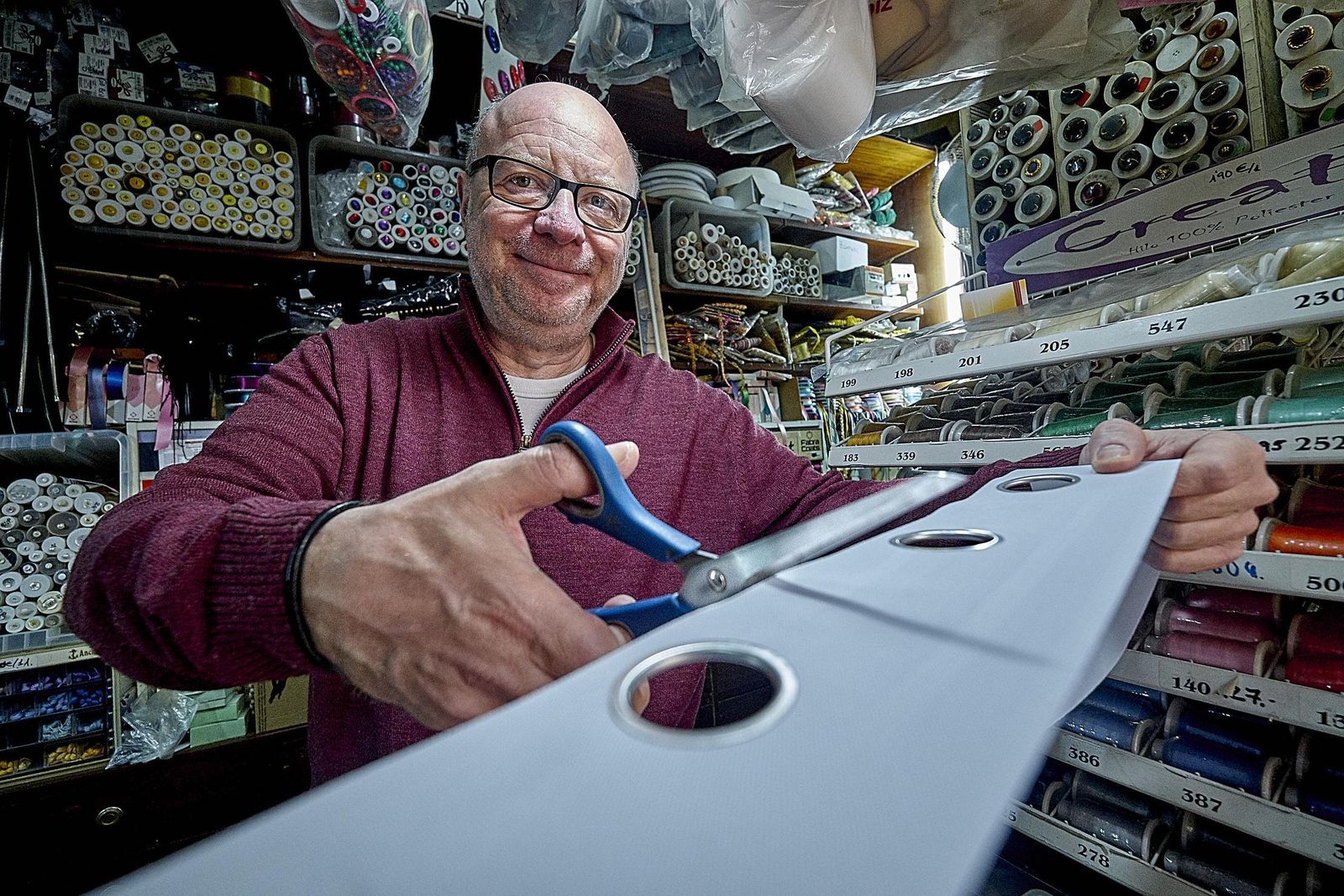 Luis Ramírez García se dispone a cortar una cinta de cortina con ojetes.