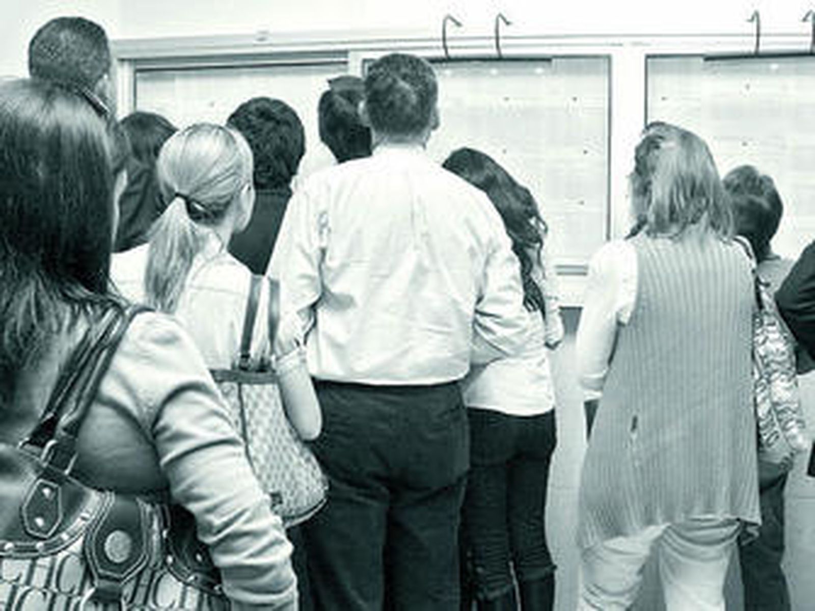 Un grupo de padres contempla las listas de alumnos admitidos de un colegio.