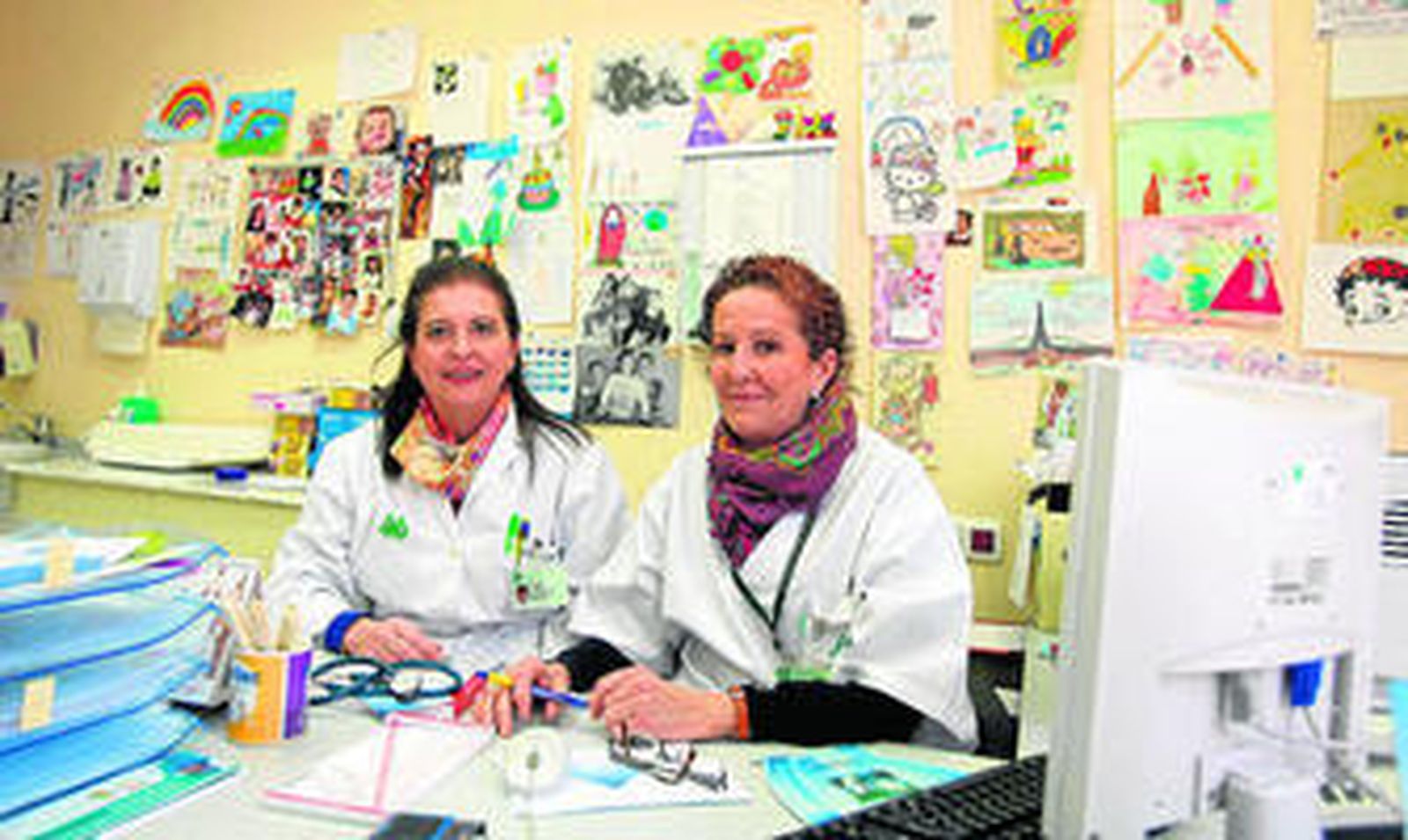 Alicia Villar (izquierda) y Mª Luz Sevillano, en su consulta de pediatría del centro de salud, con las paredes llenas de dibujos de sus pacientes.