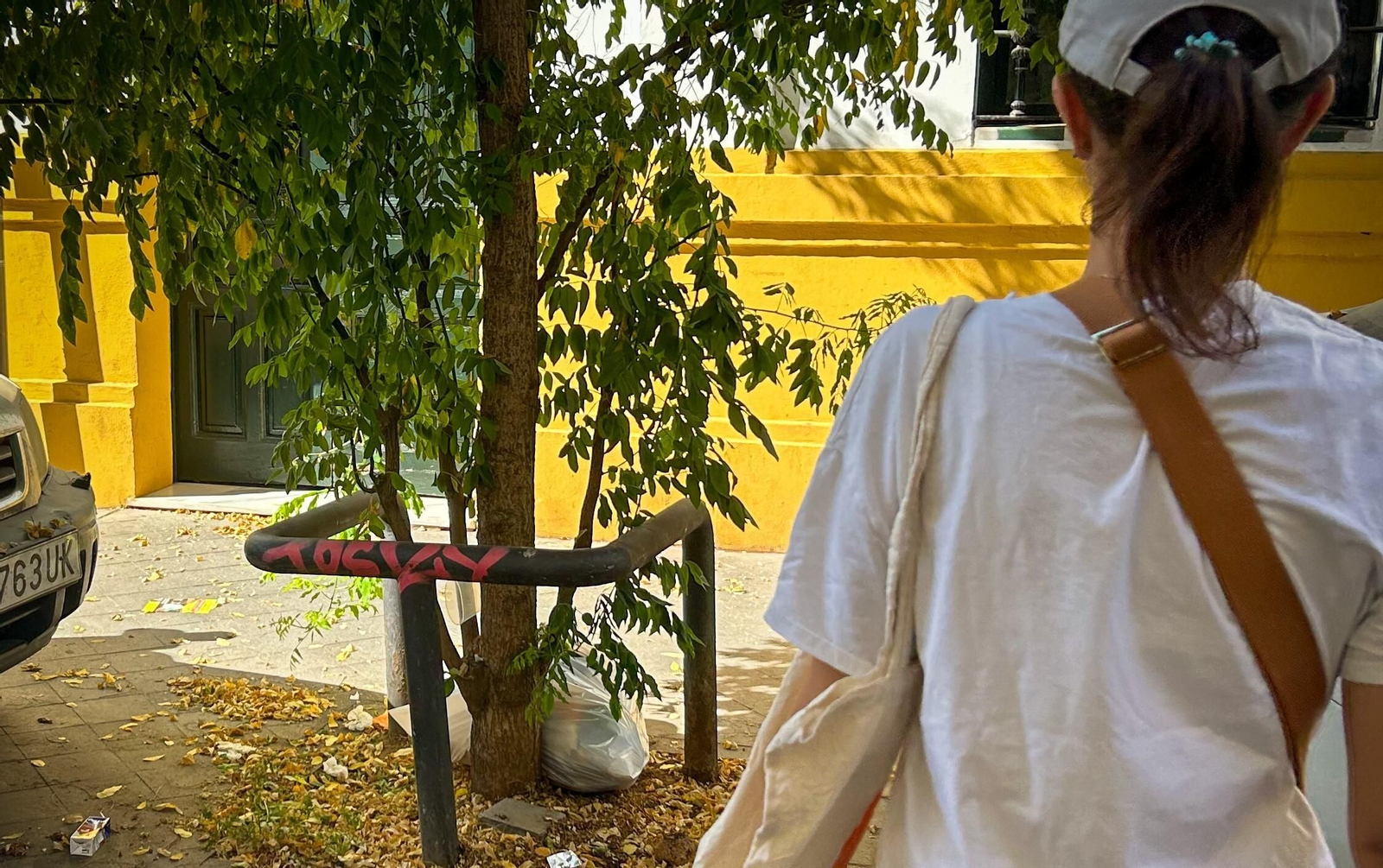 Una vecina de la calle Matahacas pasa cerca de una bolsa de basura tirada junto a un árbol.