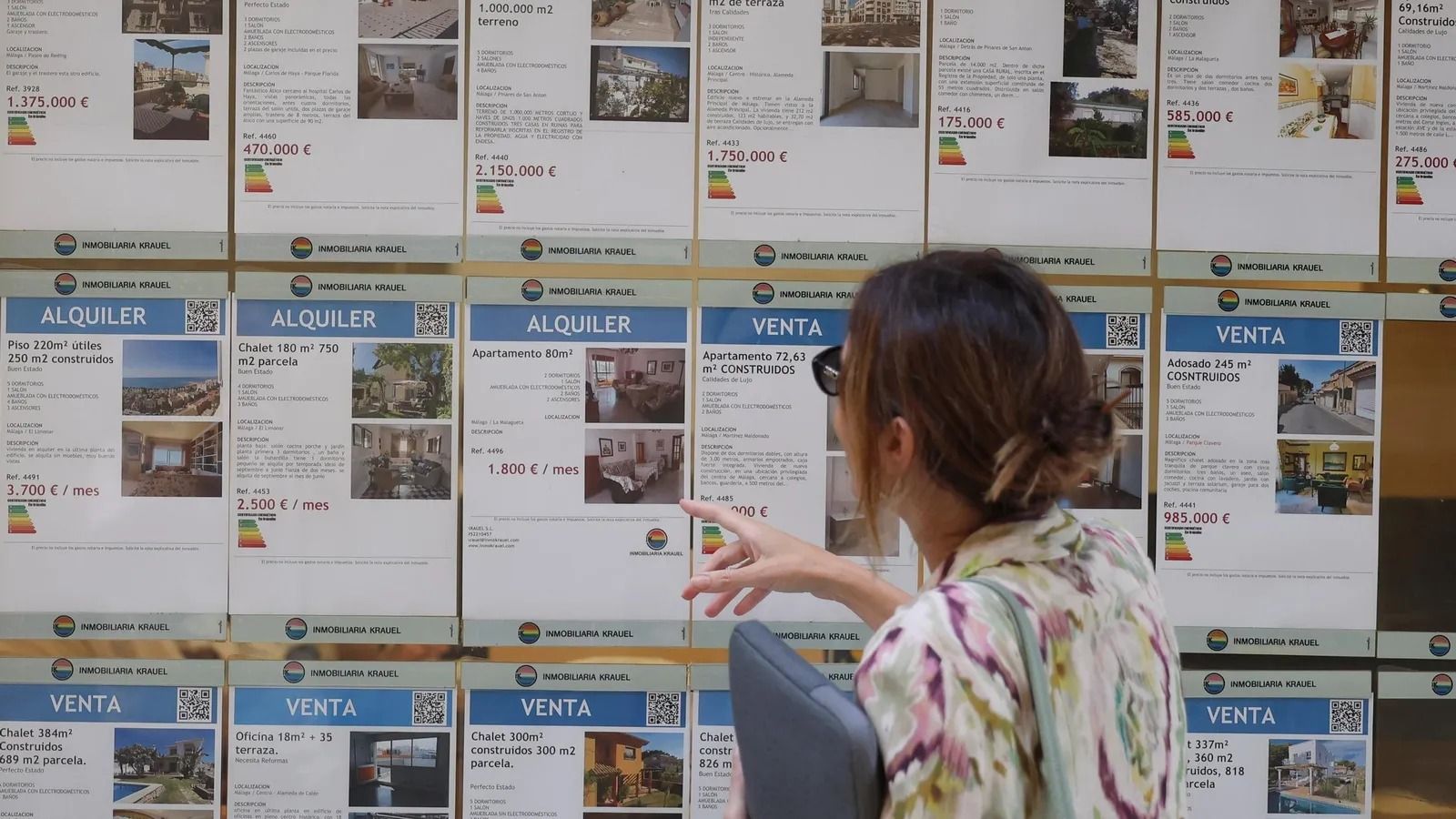 Una mujer mira las ofertas de viviendas en una inmobiliaria.
