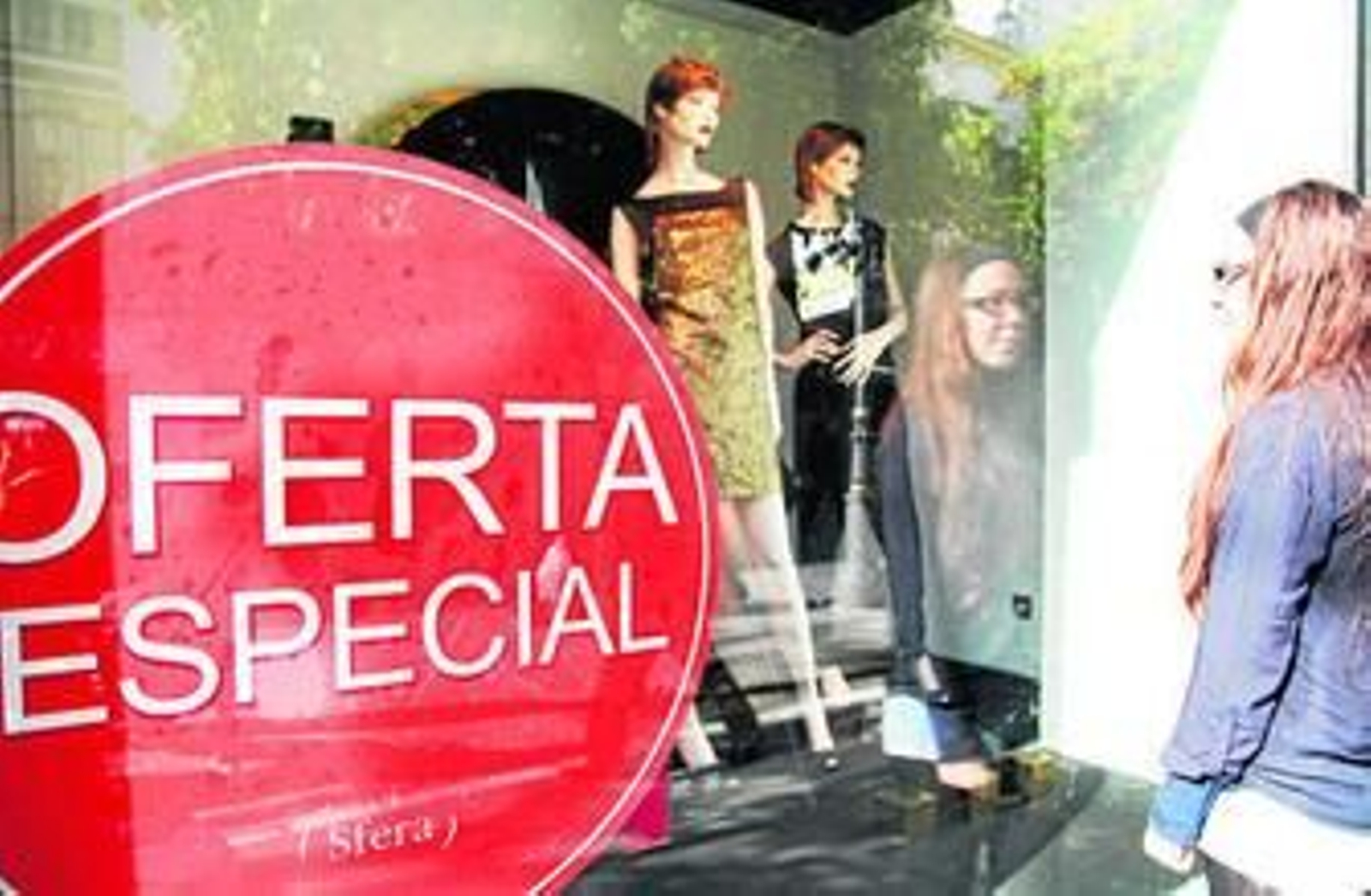 Una joven mira un escaparate con ofertas especiales en una conocida tienda del centro.
