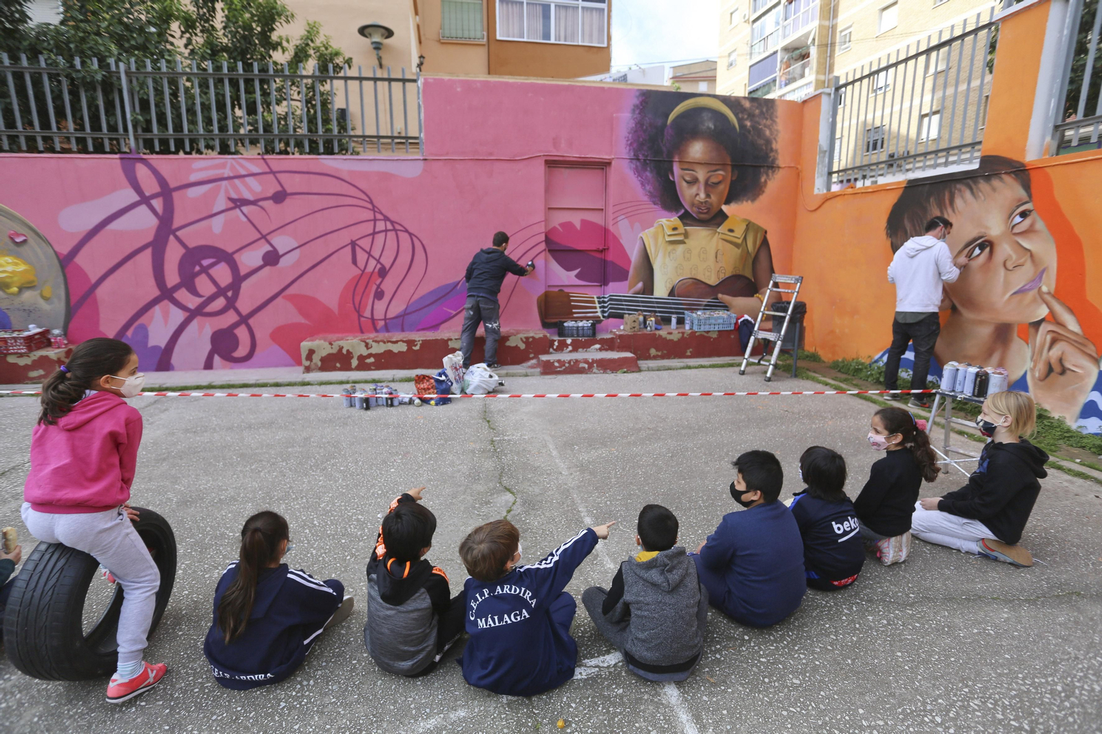 Alumnos del colegio Ardira observan a los artistas realizar el mural.