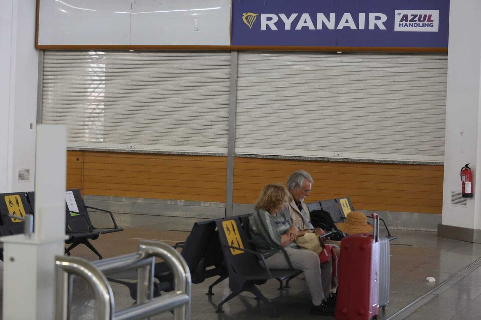 Una pareja espera sentada a las puertas de un mostrador de Ryanair.