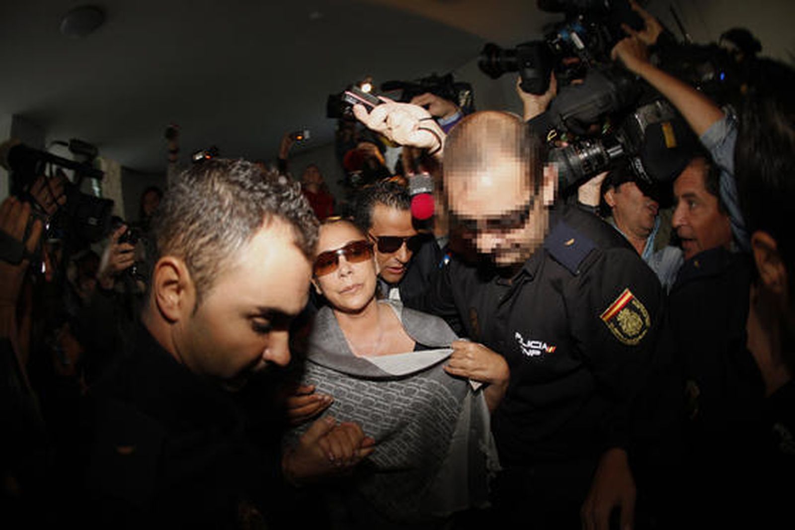 Isabel Pantoja avanza acompañada por un policía entre los medios. / Reuters