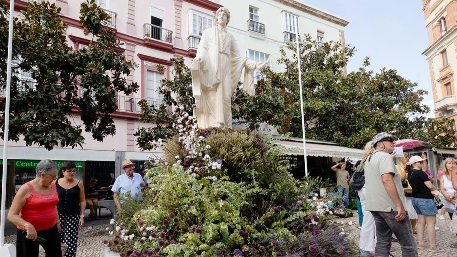 La estatua de Columela adornada con flores.