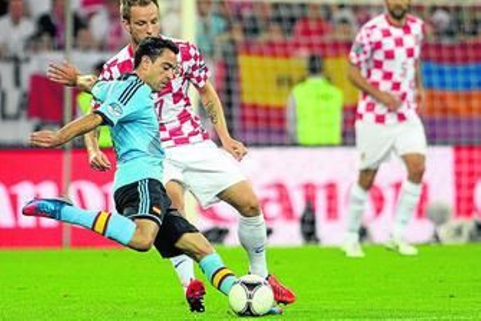 Xavi intenta desplazar el balón, con el marcaje cercano de Rakitic.