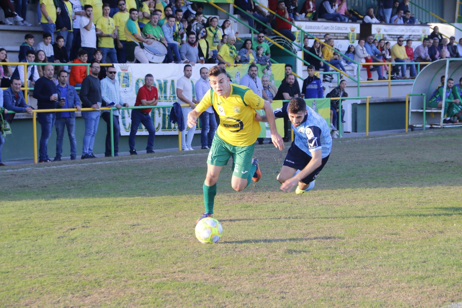 Álex Guti avanza con el balón mientras un defensor del Rota cae