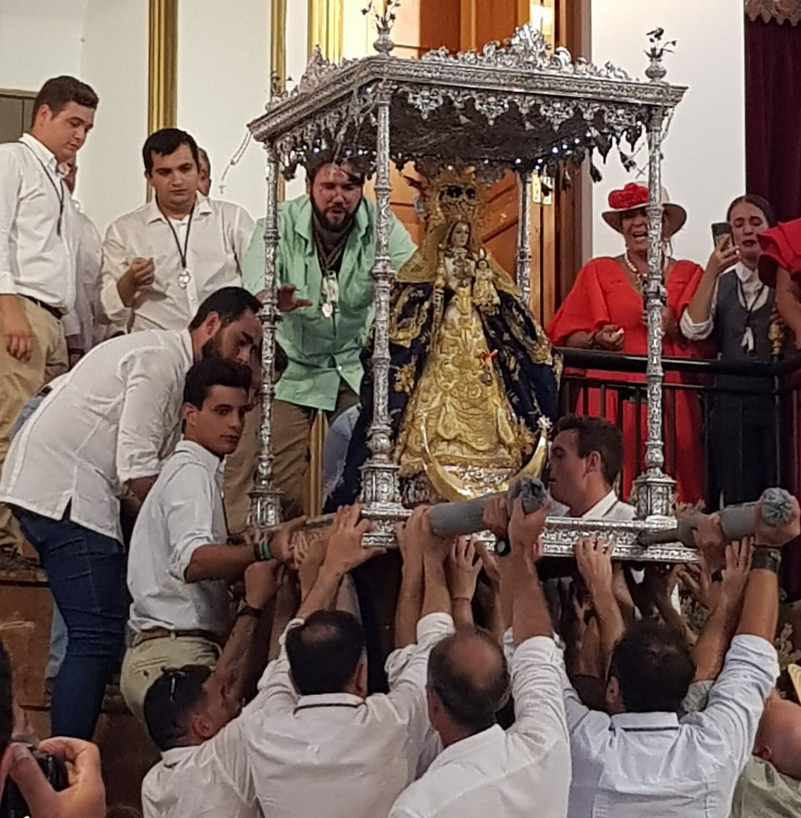 Vecinos del pueblo descienden la imagen de la Virgen del altar de la ermita.