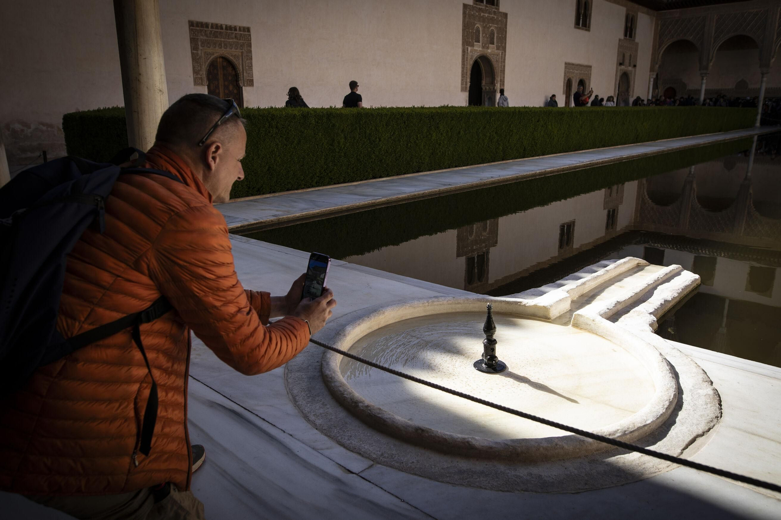 Un visitante toma una foto de la fuente del Patio de los Arrayanes.