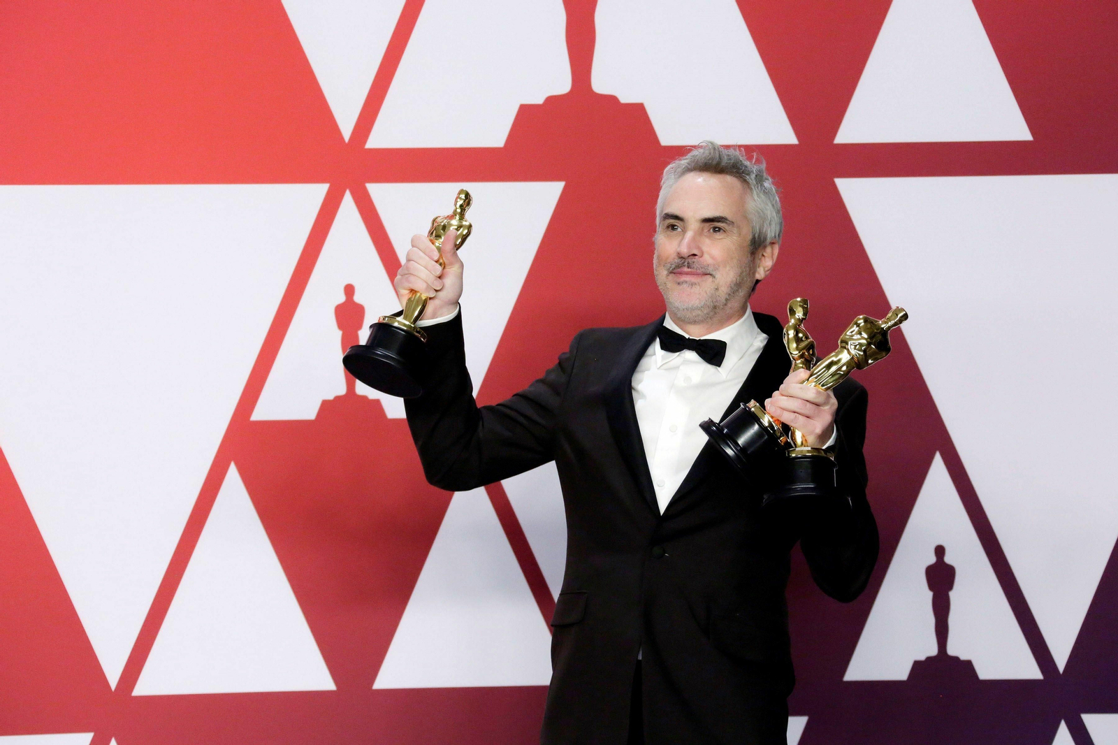El director mexicano Alfonso Cuarón posa con las estatuillas de mejor dirección, mejor fotografía y mejor película de habla extranjera por 'Roma'.