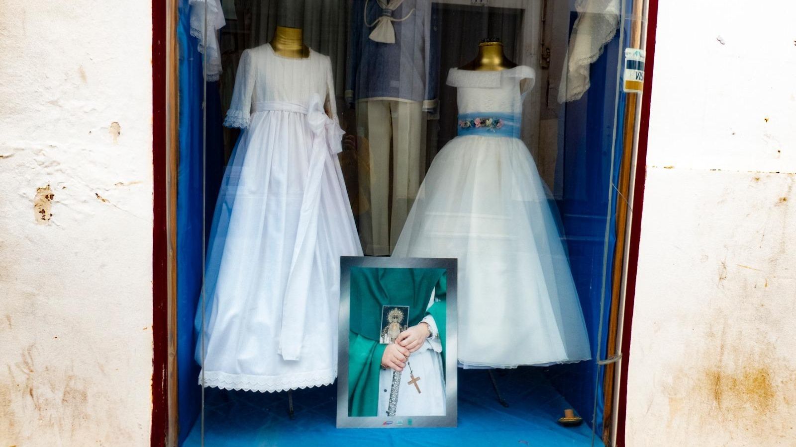 Decoración cofrade en un establecimiento comercial del centro, junto a trajes de comunión.