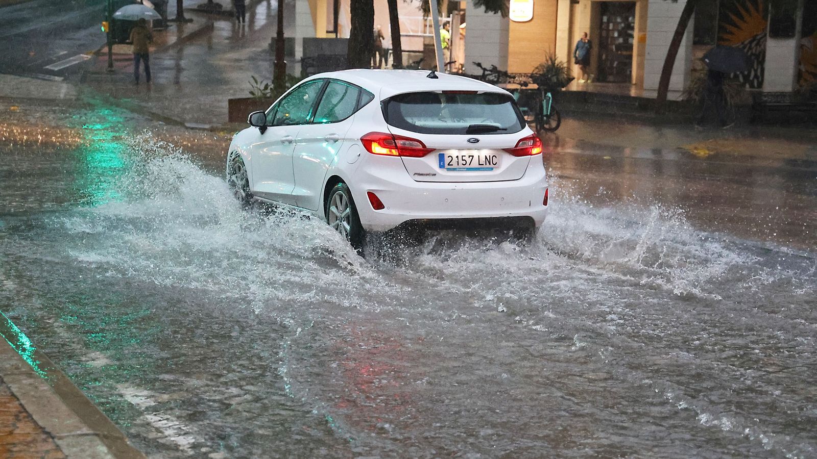 Un coche trata de conducir por una de las calles anegadas de la capital.