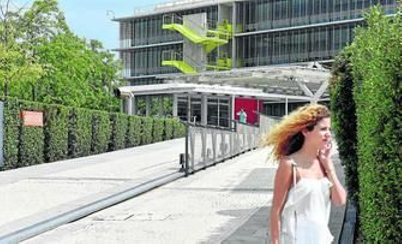 Una joven camina frente a la puerta de entrada de Palmas Altas, la sede sevillana de Abengoa.