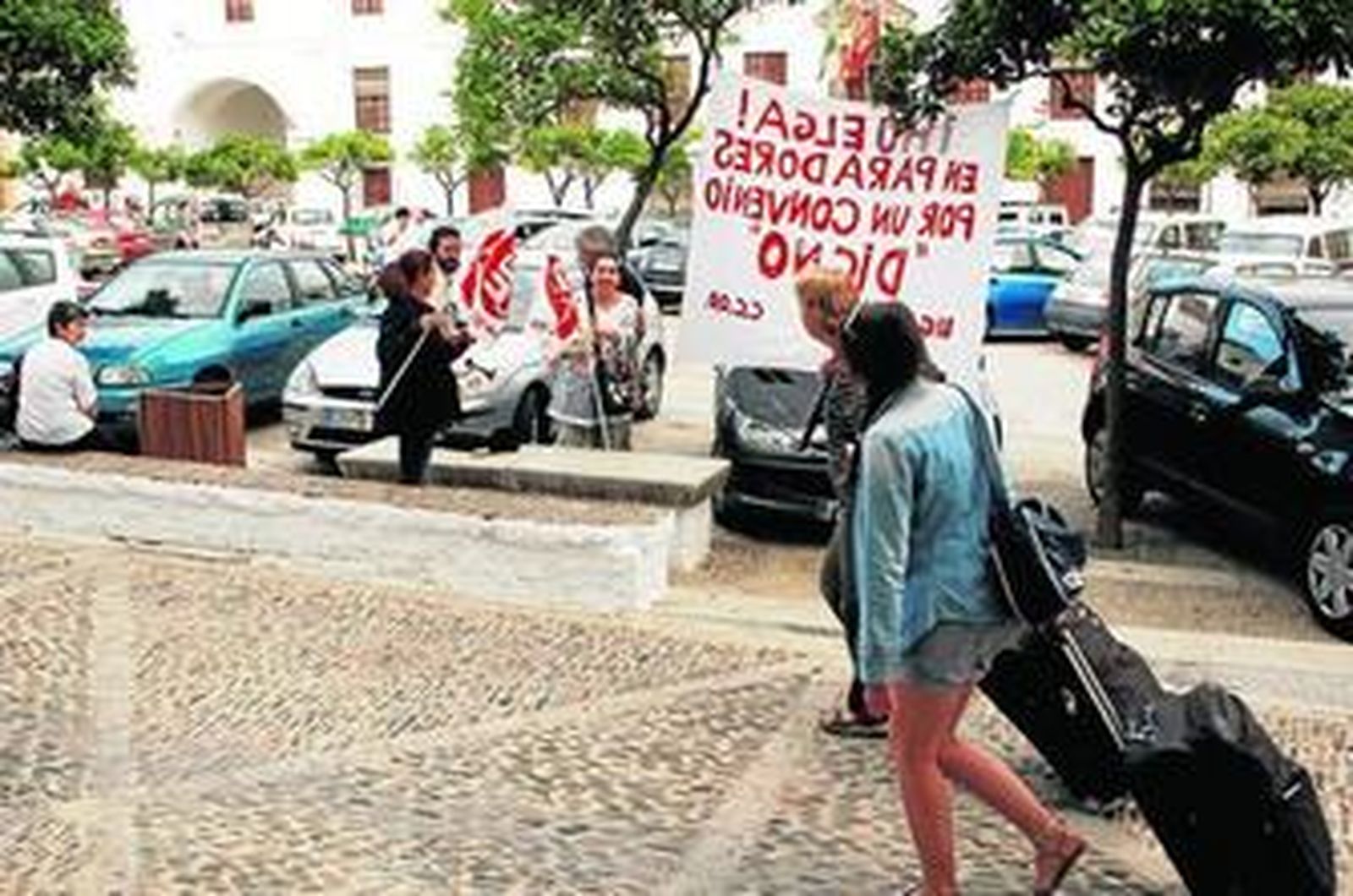 Una turista se dirige al Parador de Arcos y sus trabajadores se manifiestan a las puertas del hotel.