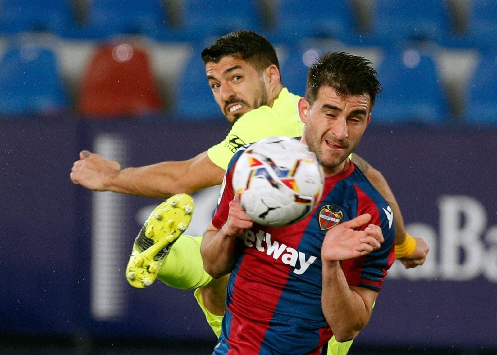 Suárez estrella un balón contra un rival.