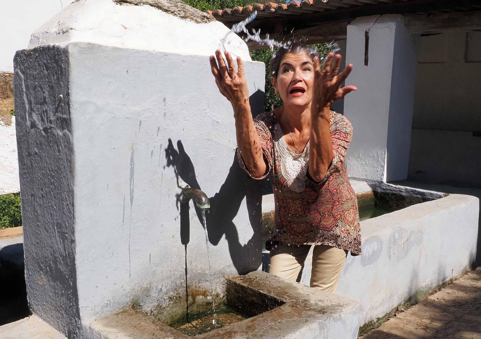 La alcaldesa en funciones de Cortelazor, Paloma Samper, muestra el pequeño hilo de agua que brote de una fuente que abasteció los lavaderos públicos del municipio