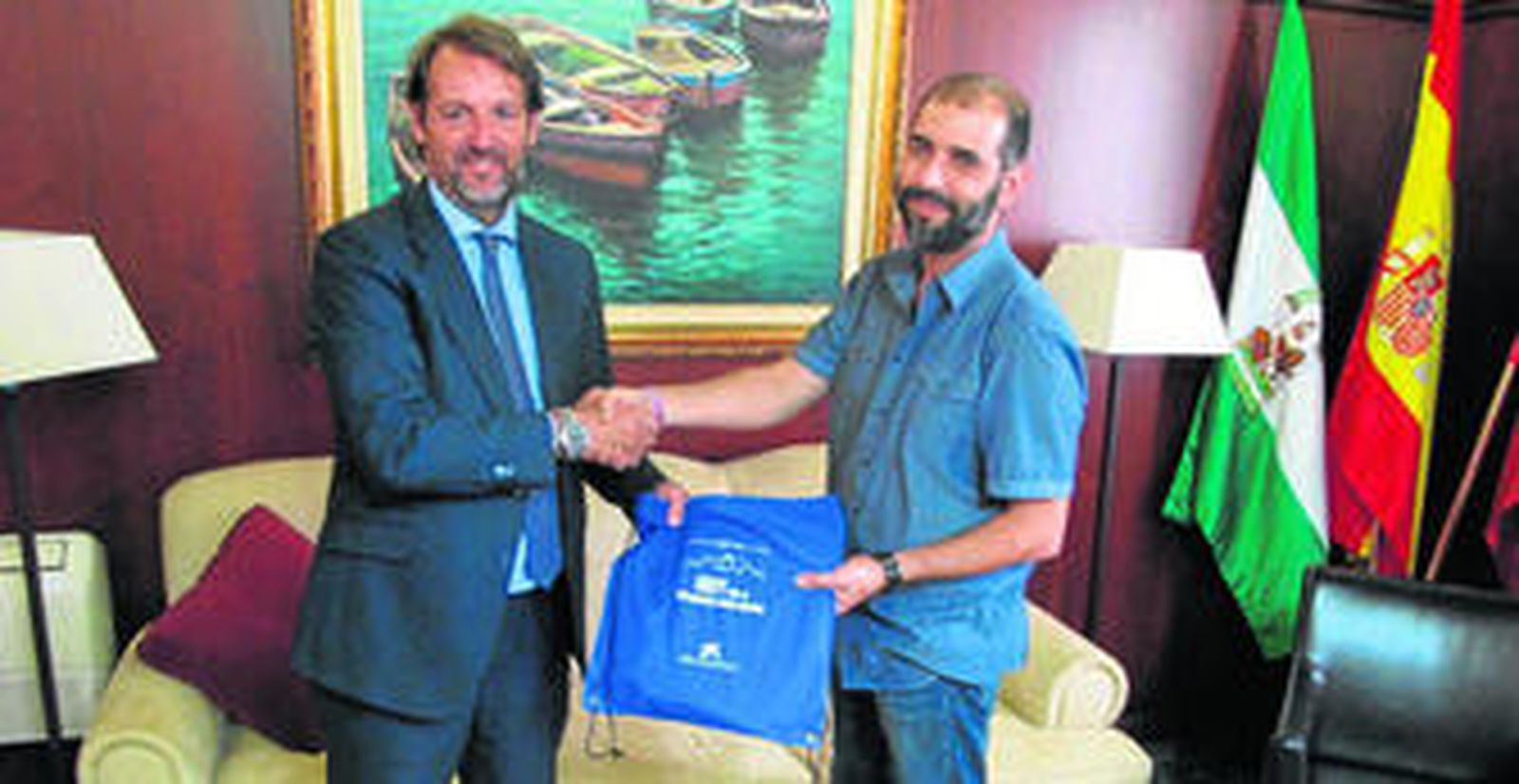 El representante de La Caixa, Luis Llerena, entrega uno de los kit que reciben los escolares al alcalde de Puerto Real, Antonio Romero.