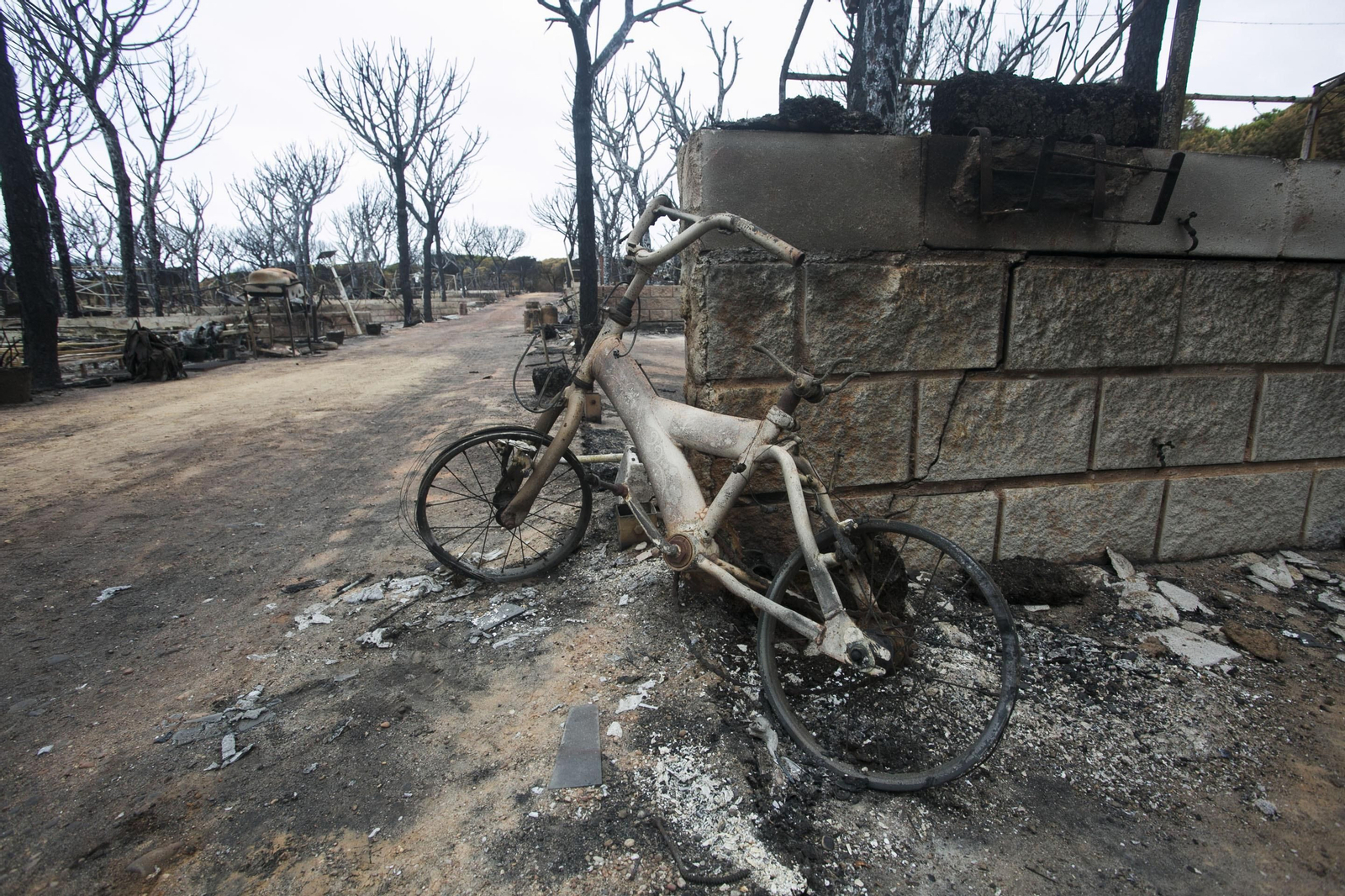 Área quemada del camping Doñana de Mazagón, con una bicicleta infantil calcinada en primer término.