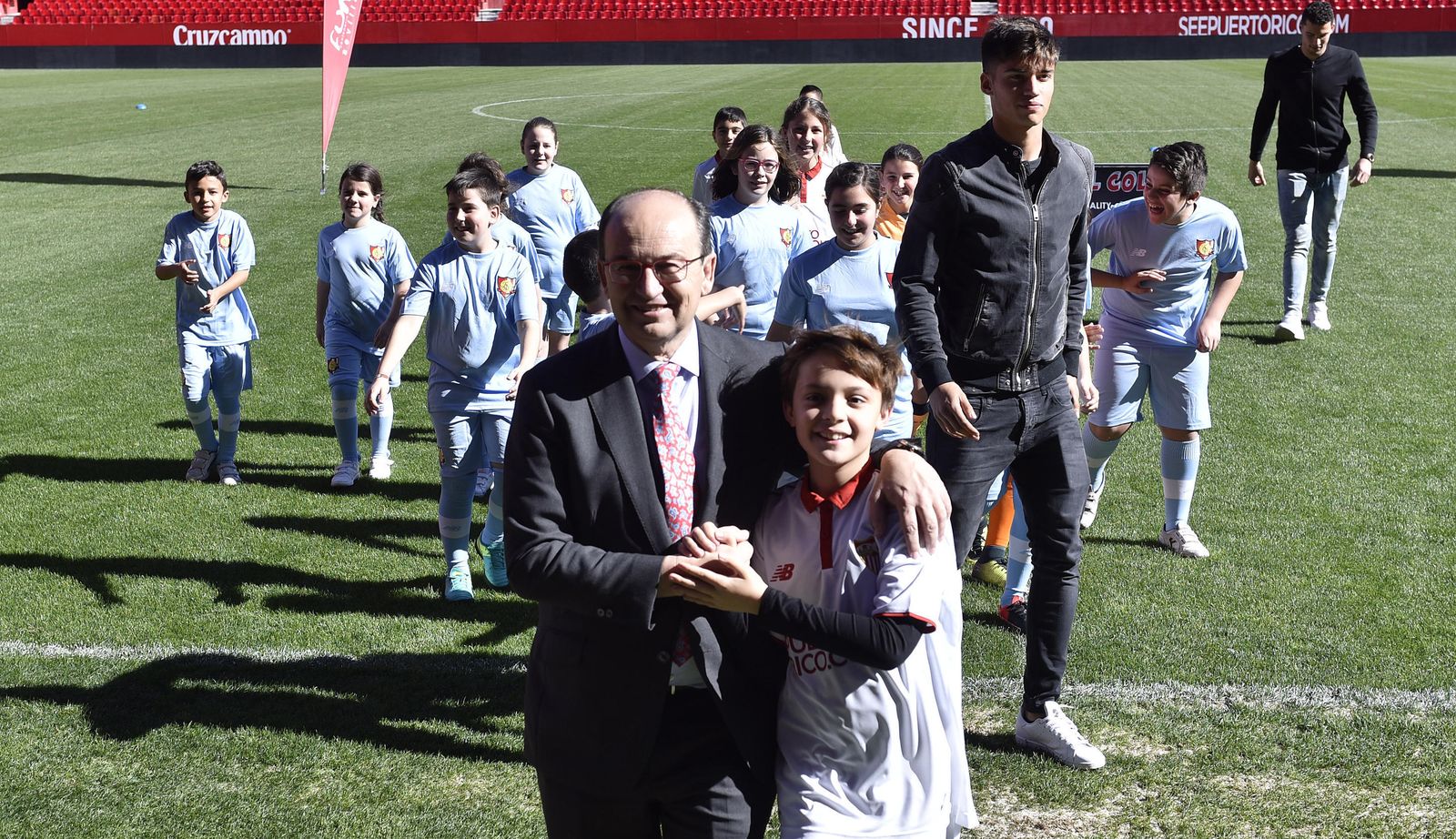 El presidente del Sevilla bromea en el césped con uno de los niños.