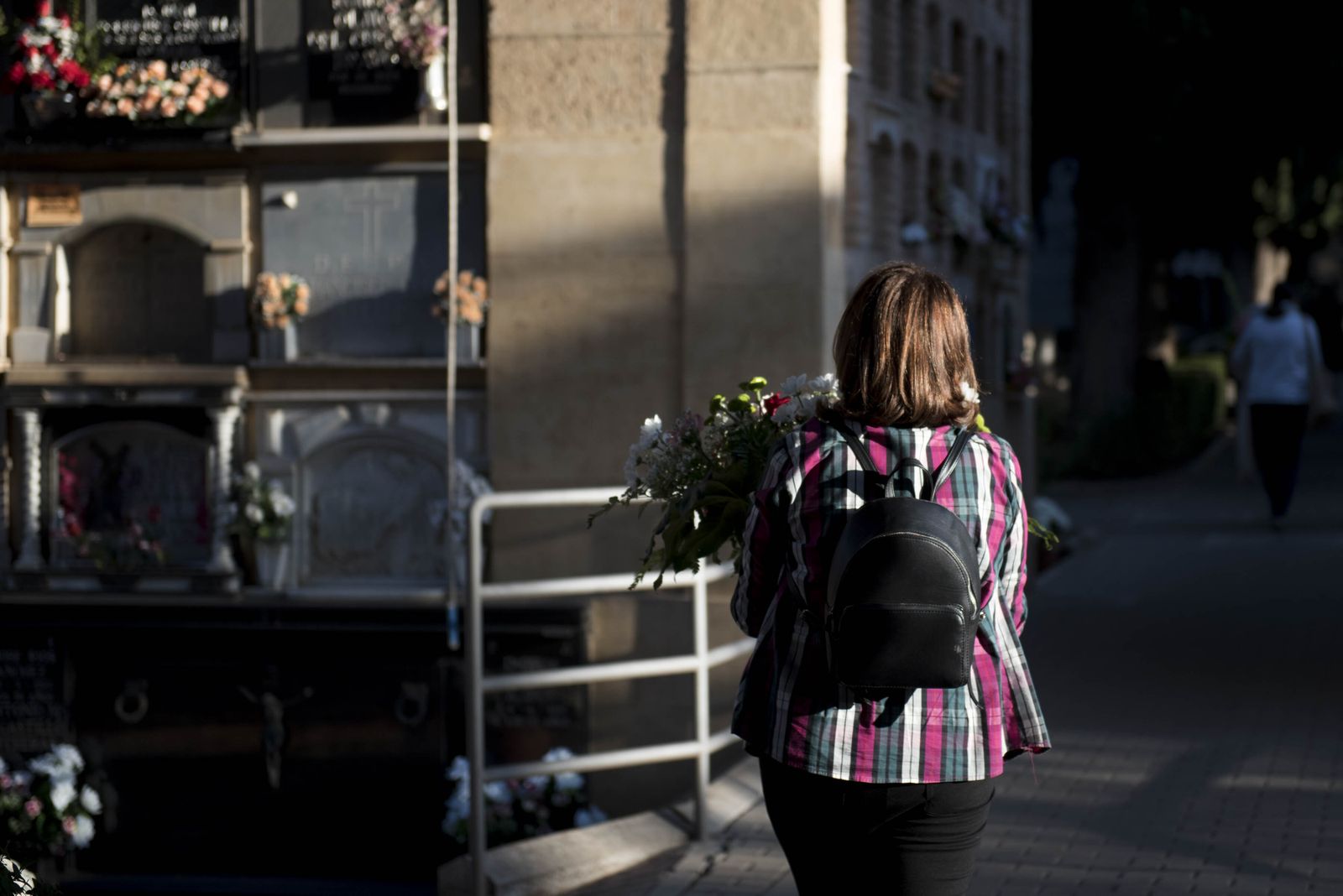 Una mujer entrega flores en la lápida de un familiar