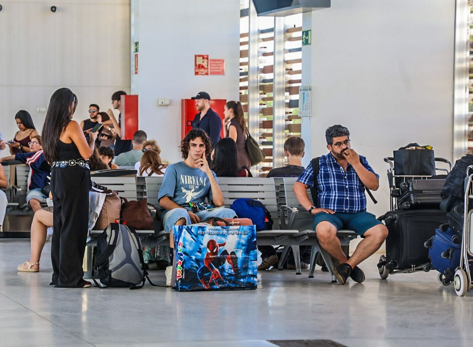 Varios pasajeros de tren esperan en la estación onubense.