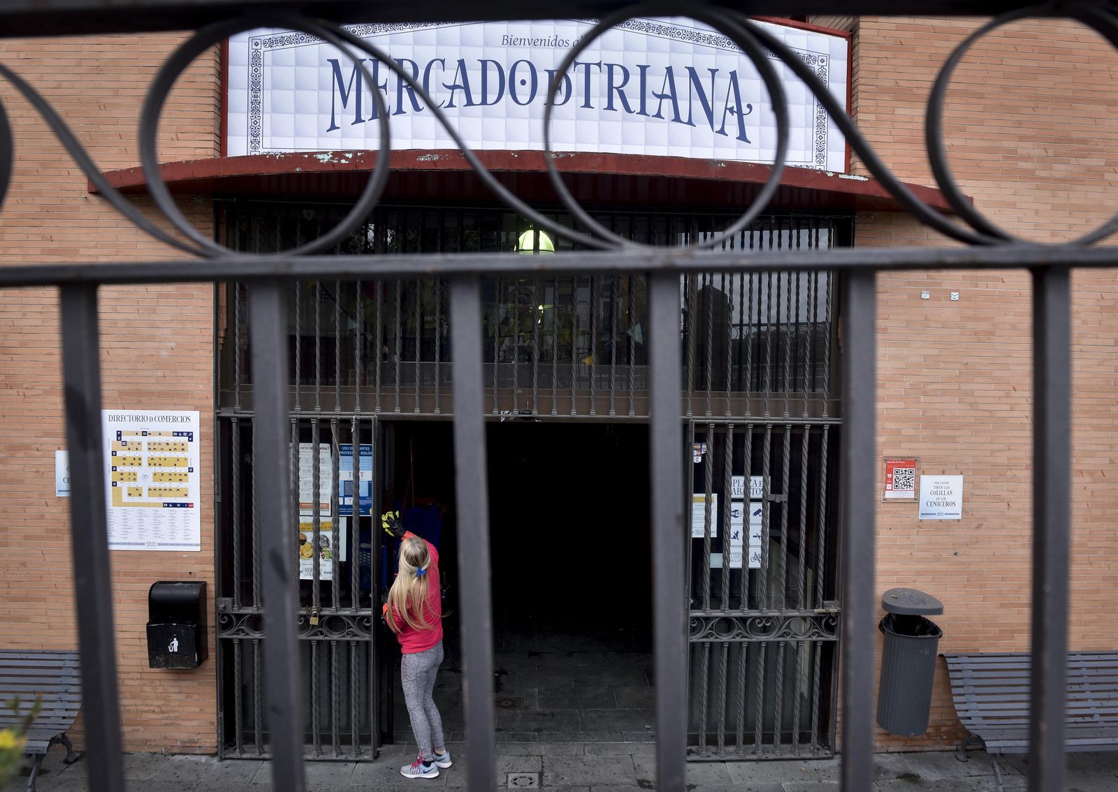 Una mujer limpia la puerta del mercado de Triana, hace unos días.