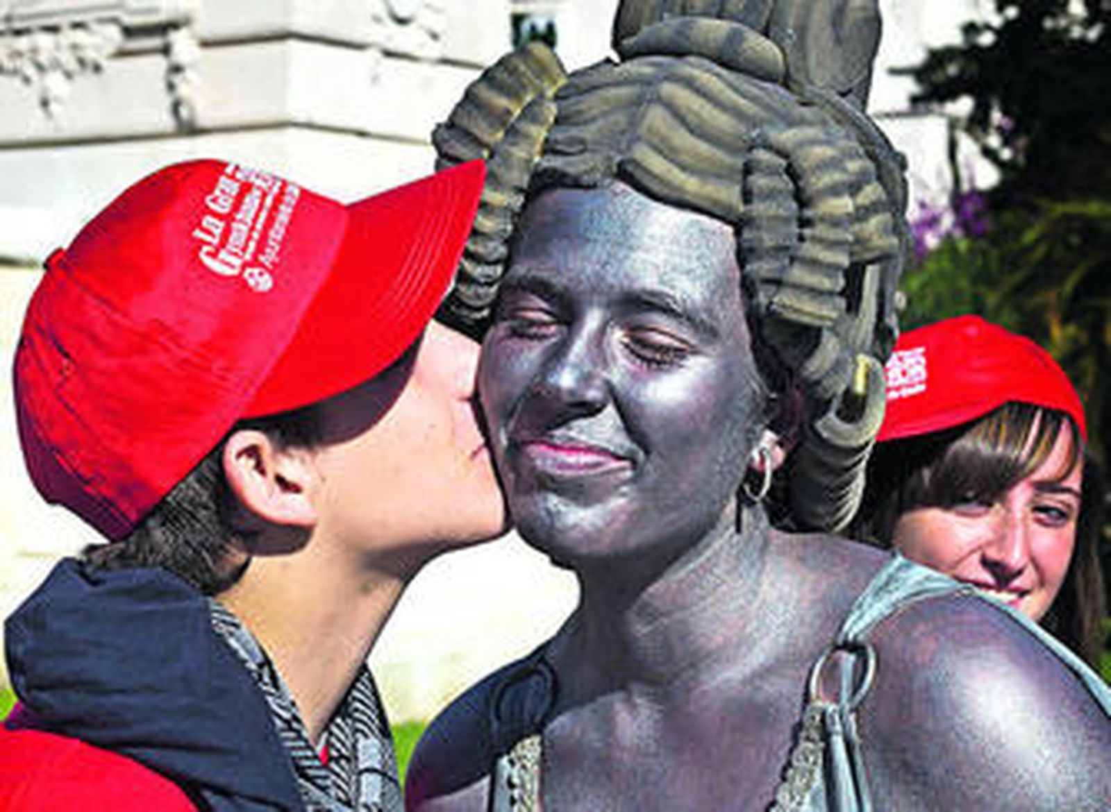 Un participante da un beso a la figura principal del monumento a las Cortes tras superar una de las pruebas de la Gymkhana del Doce.