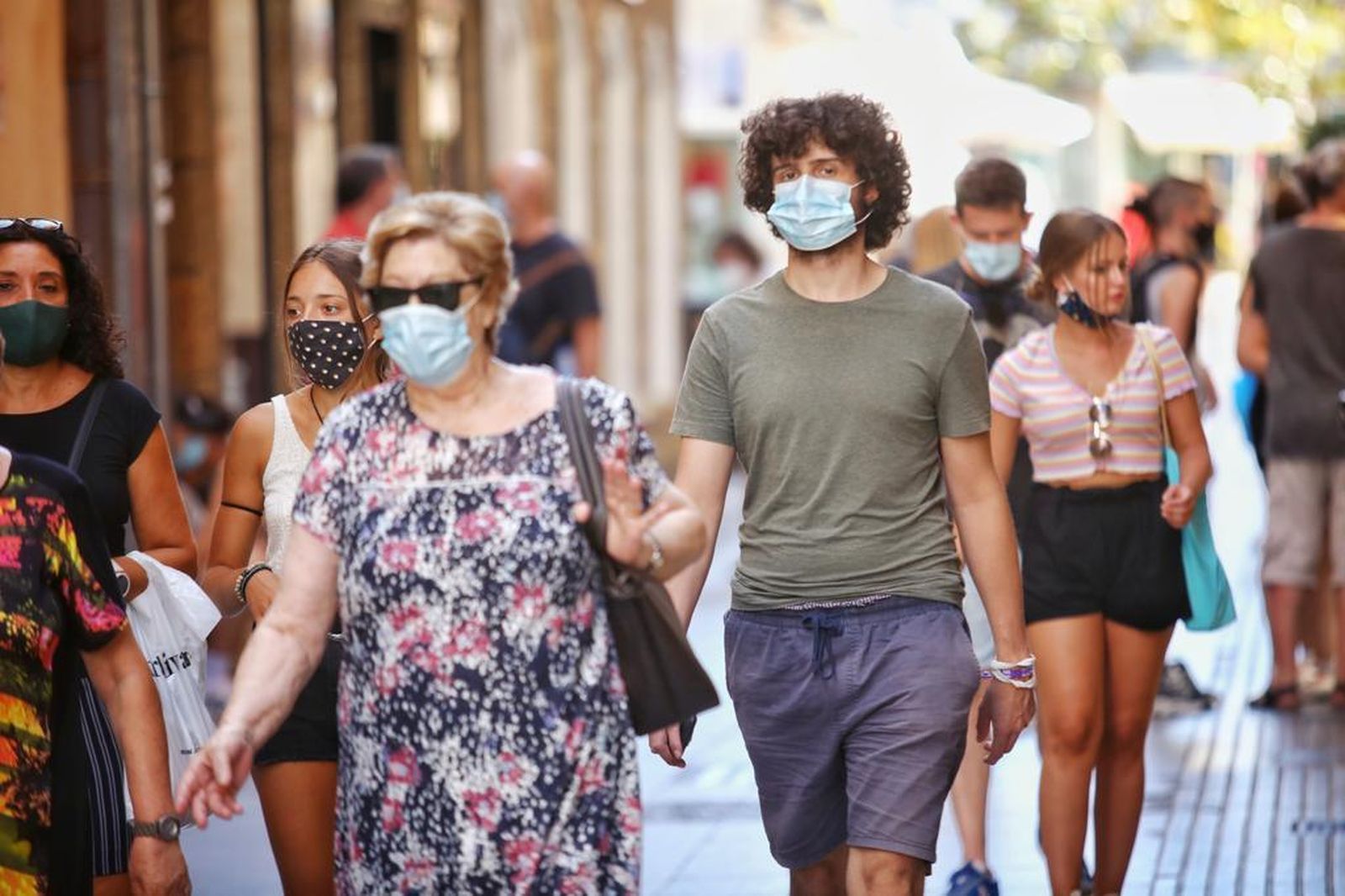 Varias personas pasean por una céntrica calle de Cádiz con mascarillas.