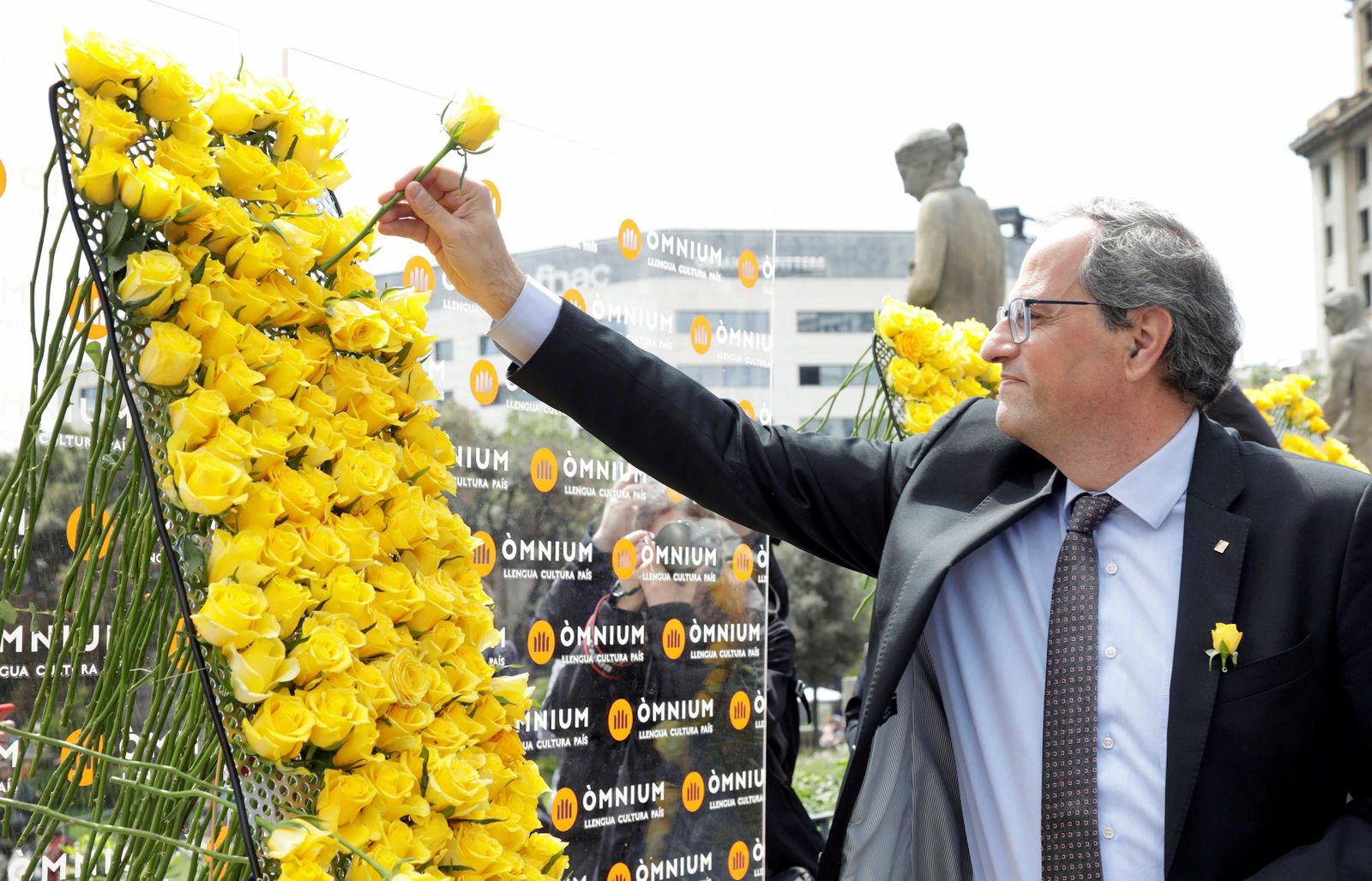 Torra coloca una rosa amarilla en un mural en Barcelona por el Día de Sant Jordi.