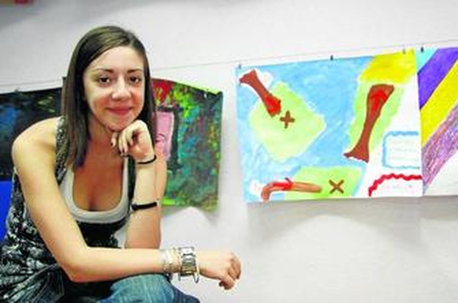 Cristina posa delante de algunos de los cuadros que se realizan en el taller de arteterapia.