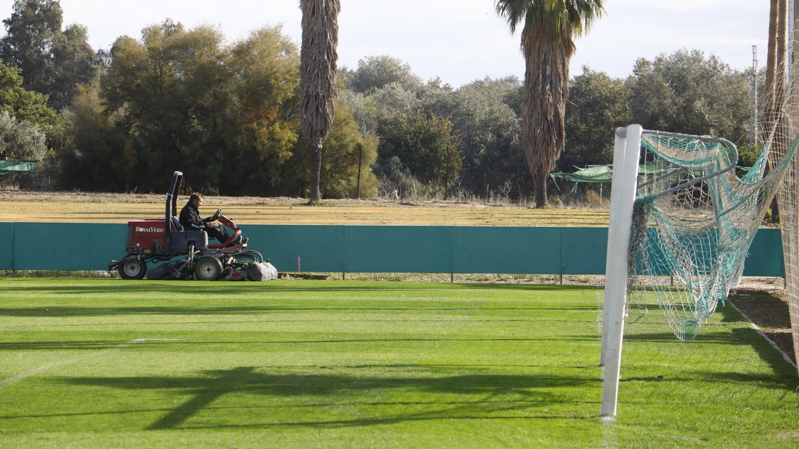 Un operario trabaja sobre el campo principal de la Ciudad Deportiva.