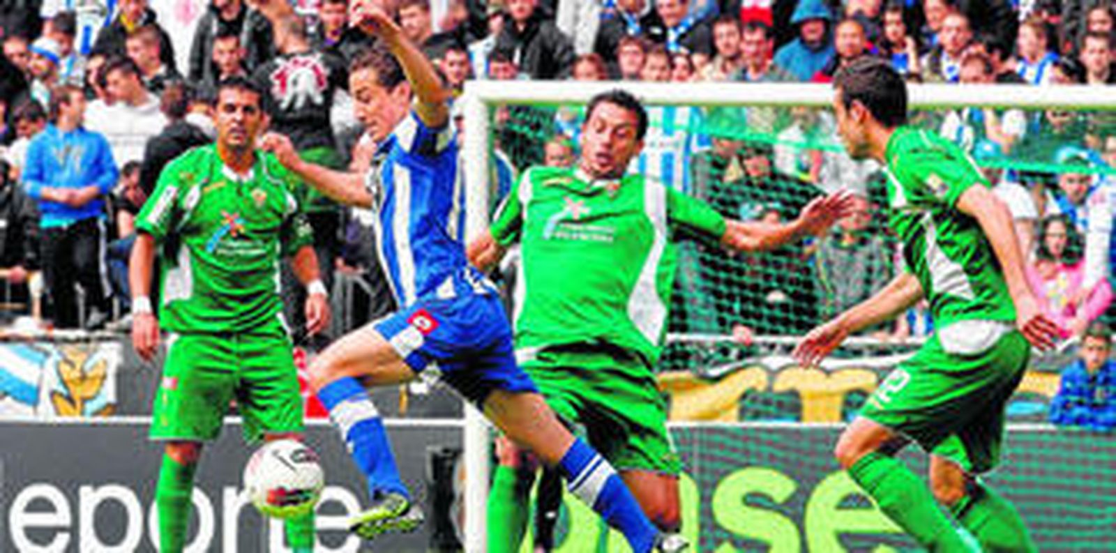 El deportivista Guardado se lleva el esférico con la pierna izquierda en presencia de tres futbolistas del Elche.