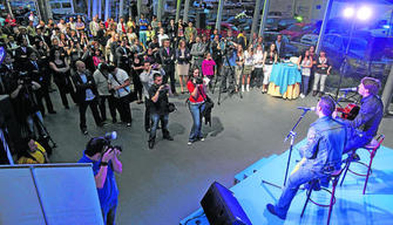 Andy y Lucas, interpretando el himno del Centenario en un abarrotado concesionario Atalaya Motor.