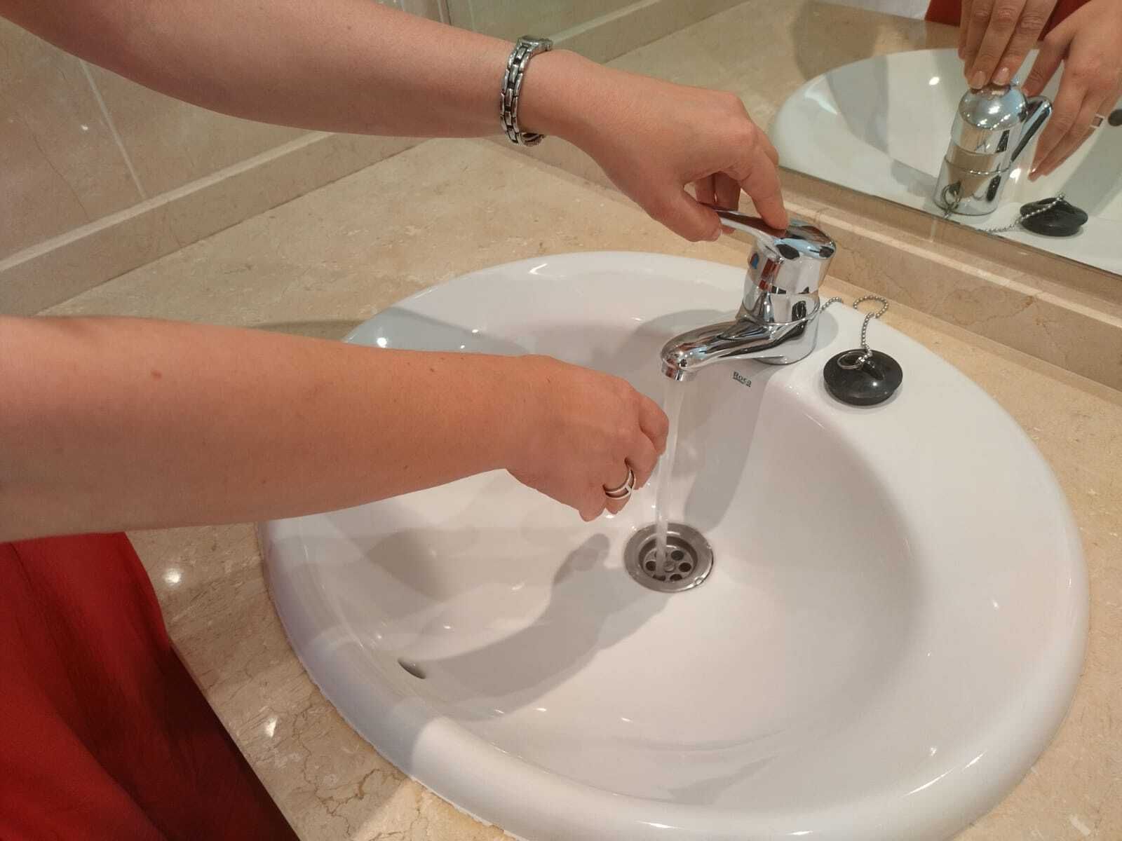 Una persona abre un grifo de agua.