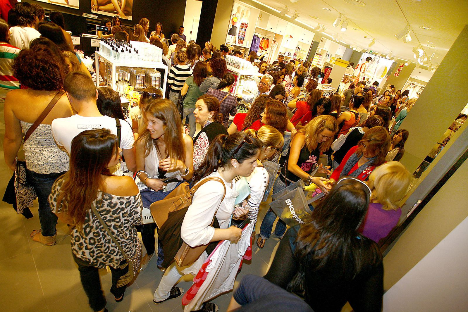 Un grupo de personas se aglomera en el interior de una tienda en época de rebajas.