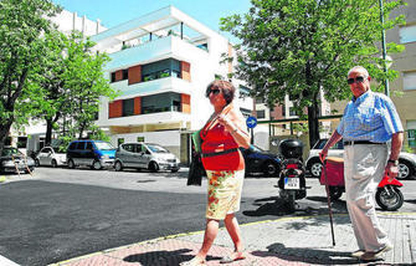 Un matrimonio pasea por una de las calles que desembocan en la calle Acacias, ante un lujoso edificio.