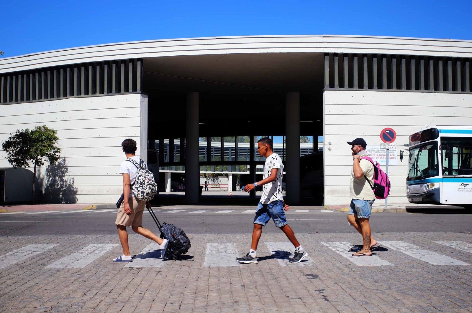 Un grupo de viajeros con sus maletas frente a la estación de autobuses.
