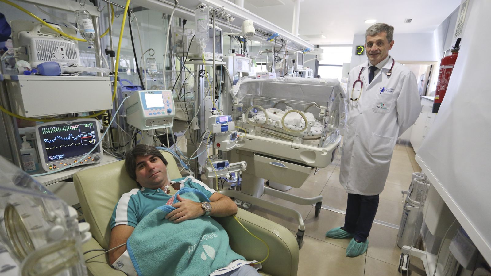 El padre acuna a uno de los niños, ante la mirada del jefe de Pediatría del Hospital Quirónsalud Málaga.