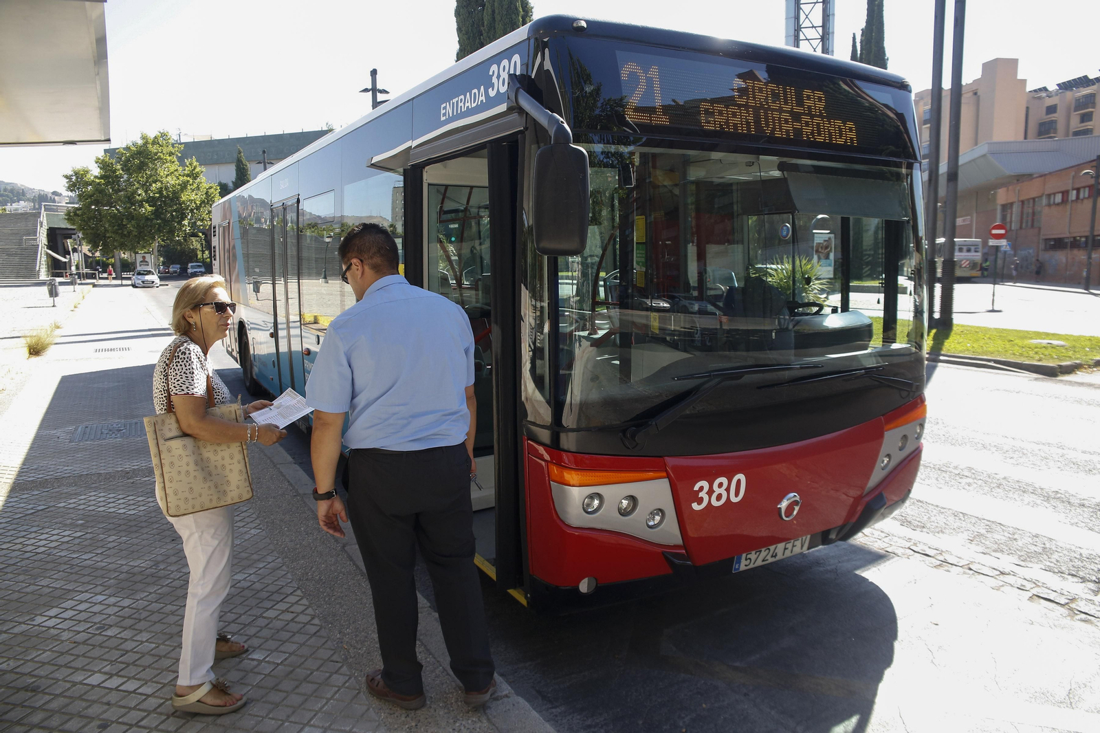 Un conductor habla con una usuaria junto al autobús.
