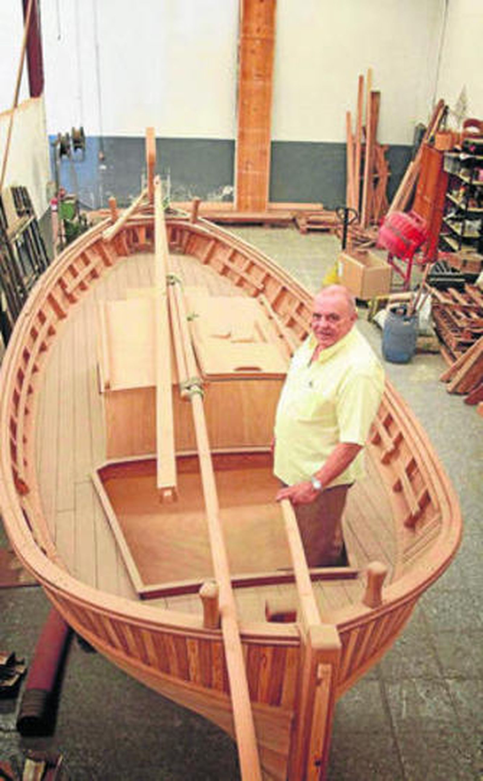 Ramón Bernal posando junto a las dos embarcaciones que guarda en su taller.