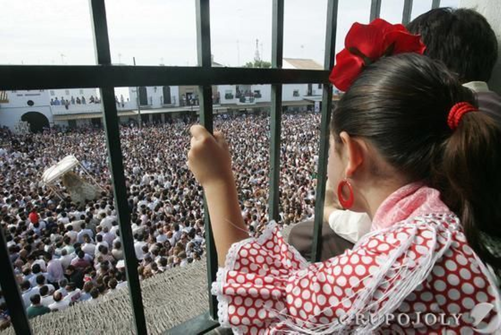 Una romera contemplando tras una ventana de la casa de la hermandad de Jerez el paso de la Virgen.

Foto: Pascual