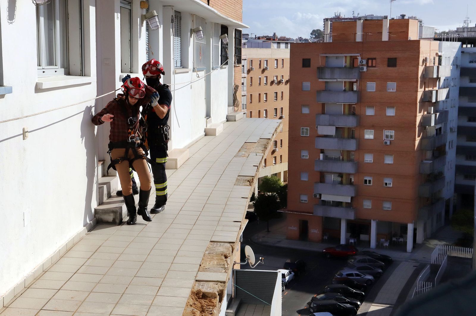 Un bombero evacua a una vecina de un bloque de viviendas en Zafra, donde se desprendió la estructura de un balcón.